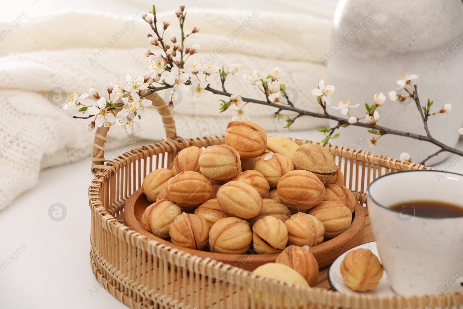 Photo of Delicious walnut shaped cookies with filling, cherry branch and cup of coffee on white table. Homemade popular biscuits from childhood
