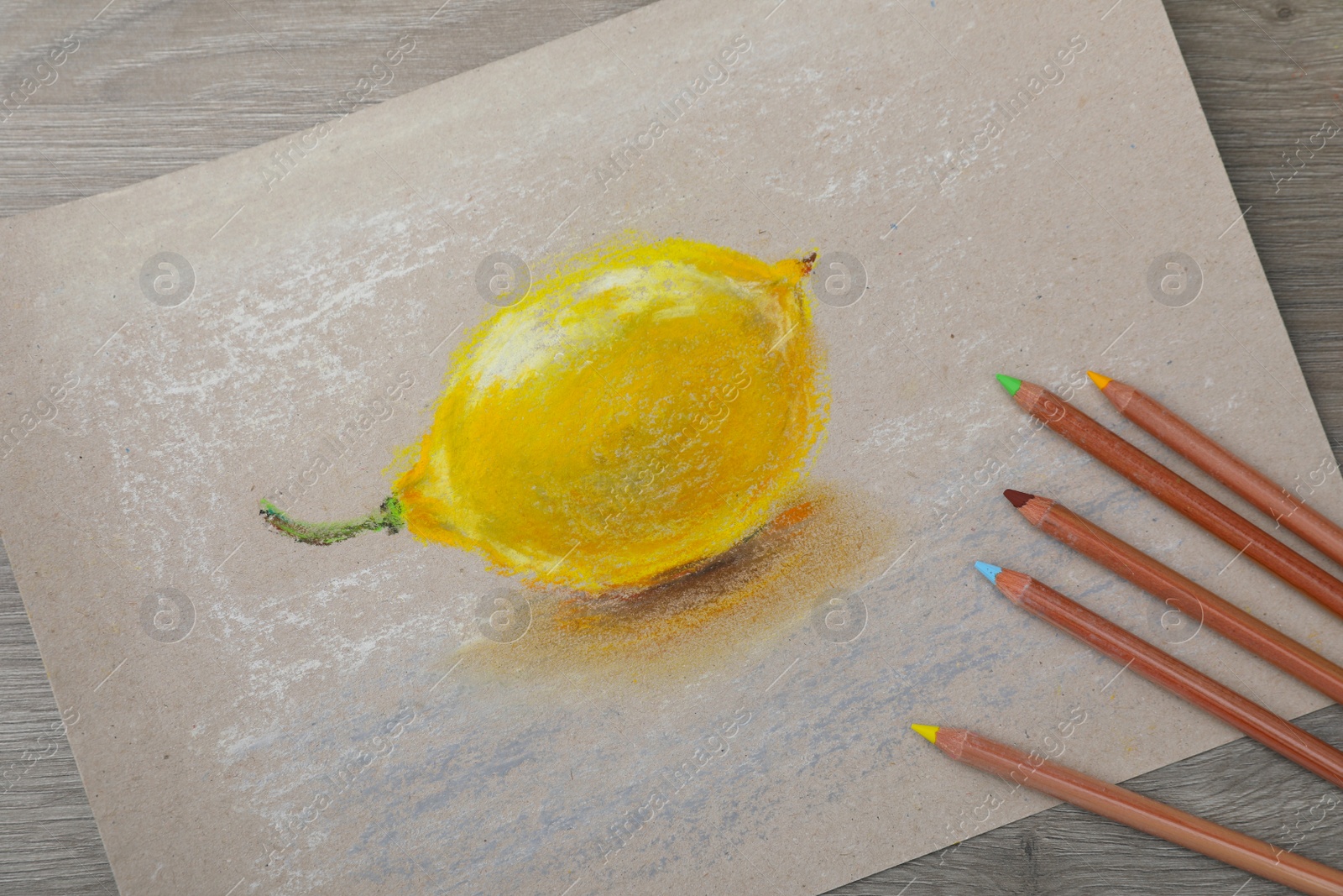 Photo of Beautiful drawing of lemon and color pencils on wooden table, flat lay