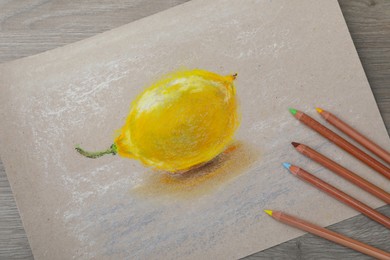 Photo of Beautiful drawing of lemon and color pencils on wooden table, flat lay