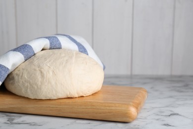 Photo of Fresh yeast dough on white marble table. Space for text