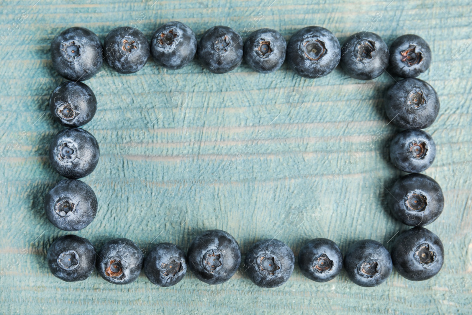 Photo of Frame of fresh ripe blueberries on wooden table, flat lay. Space for text