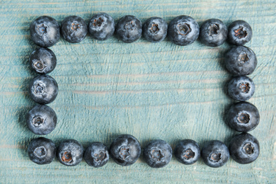 Frame of fresh ripe blueberries on wooden table, flat lay. Space for text