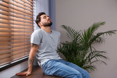 Photo of Young man relaxing near window at home