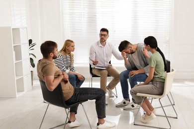 Photo of Psychotherapist working with group of drug addicted people at therapy session indoors