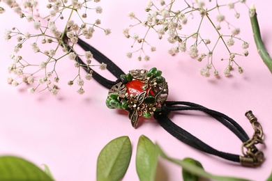 Photo of Beautiful bracelet with cornelian gemstone and flowers on pink background