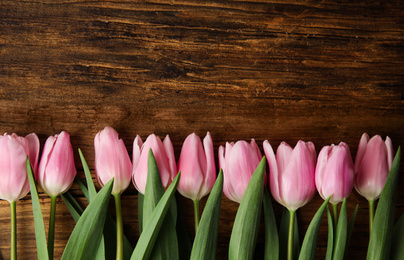 Photo of Beautiful pink spring tulips on wooden background, flat lay. Space for text