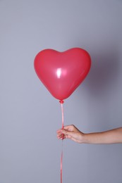 Photo of Woman holding heart shaped balloon on light background, closeup