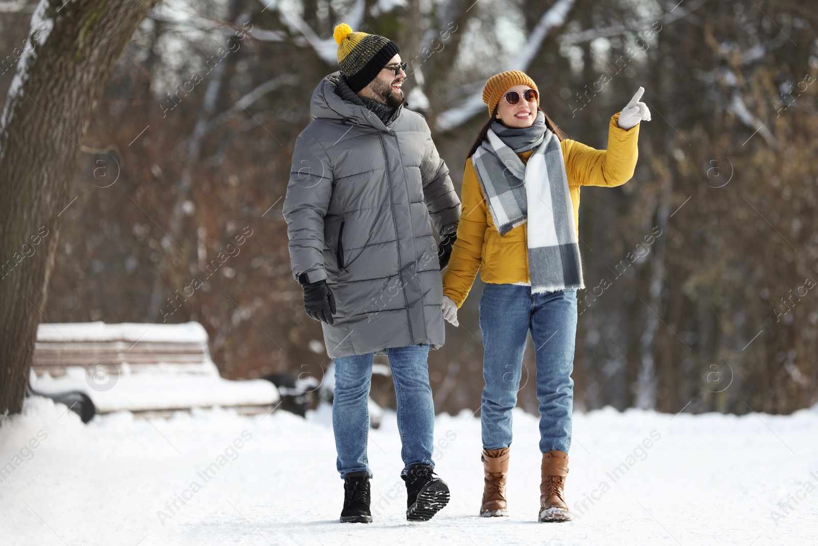 Photo of Happy young couple walking in snowy park on winter day