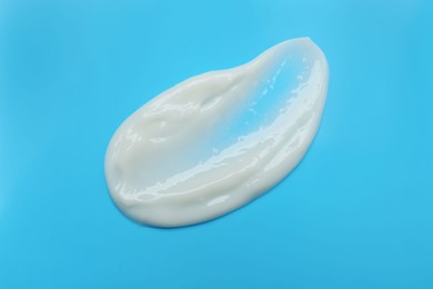Sample of hand cream on light blue background, top view