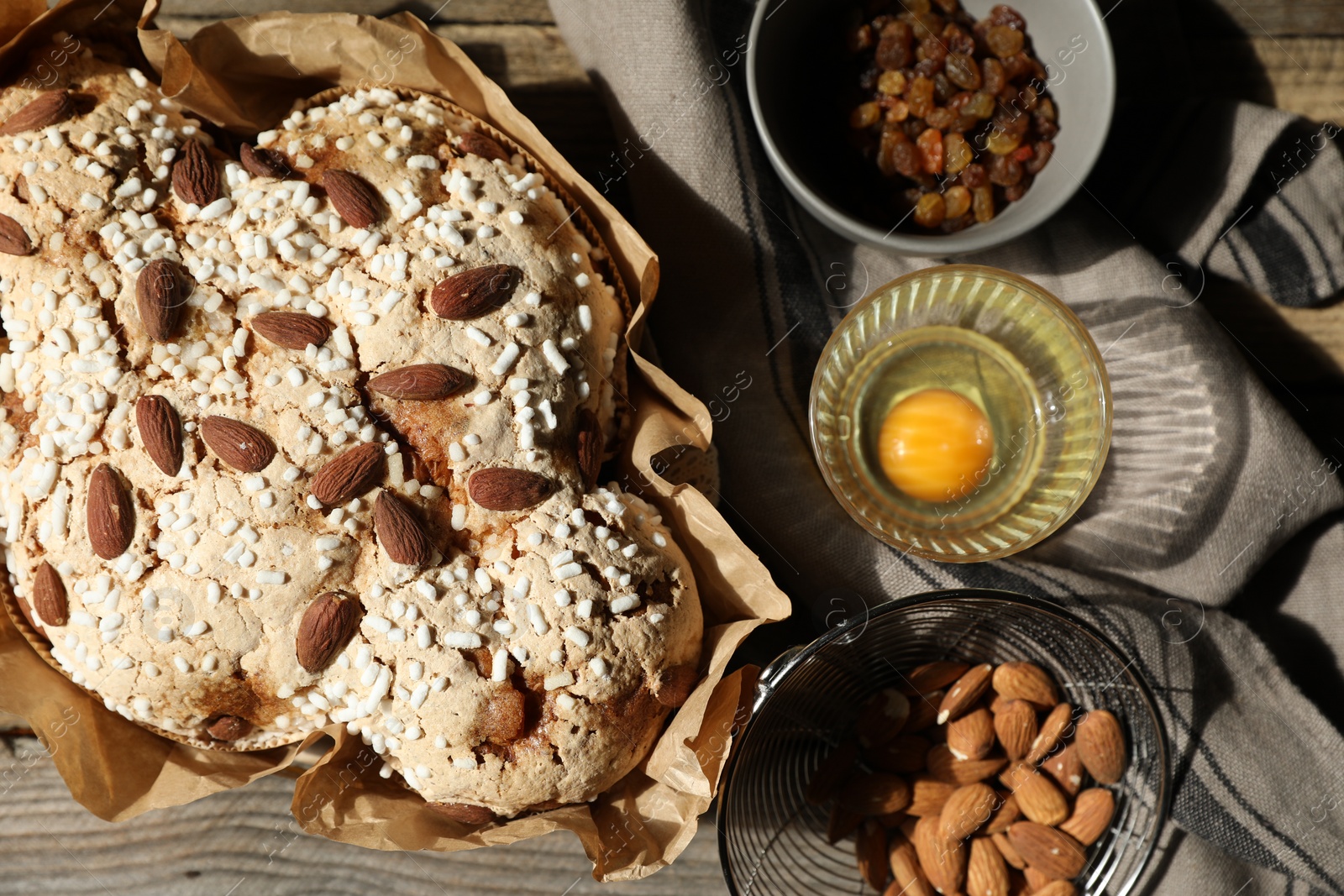 Photo of Delicious Italian Easter dove cake (traditional Colomba di Pasqua) and ingredients on wooden table, flat lay