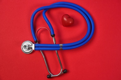 Photo of Flat lay composition with stethoscope and heart model on color background