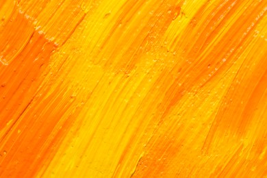 Photo of Beautiful strokes of yellow and orange oil paints as background, closeup