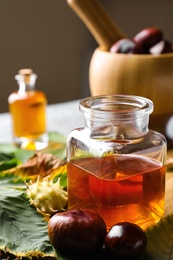 Photo of Fresh horse chestnuts and bottle of tincture on table