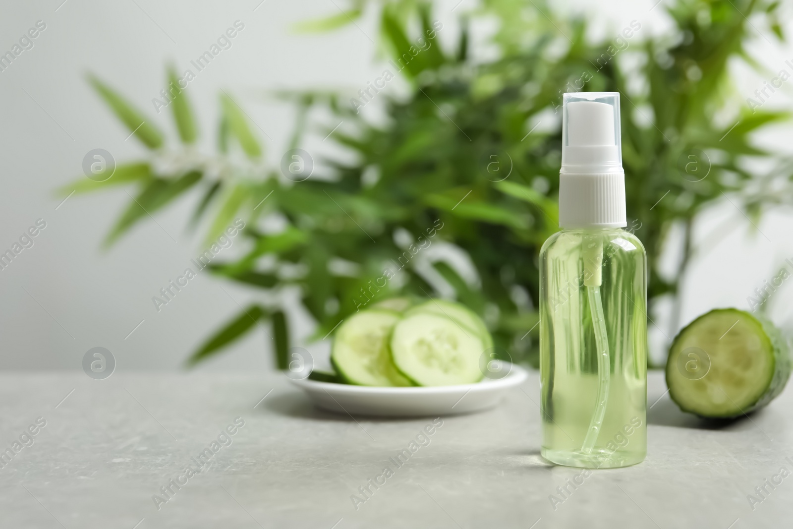 Photo of Cucumber tonic in bottle on table against blurred background. Space for text