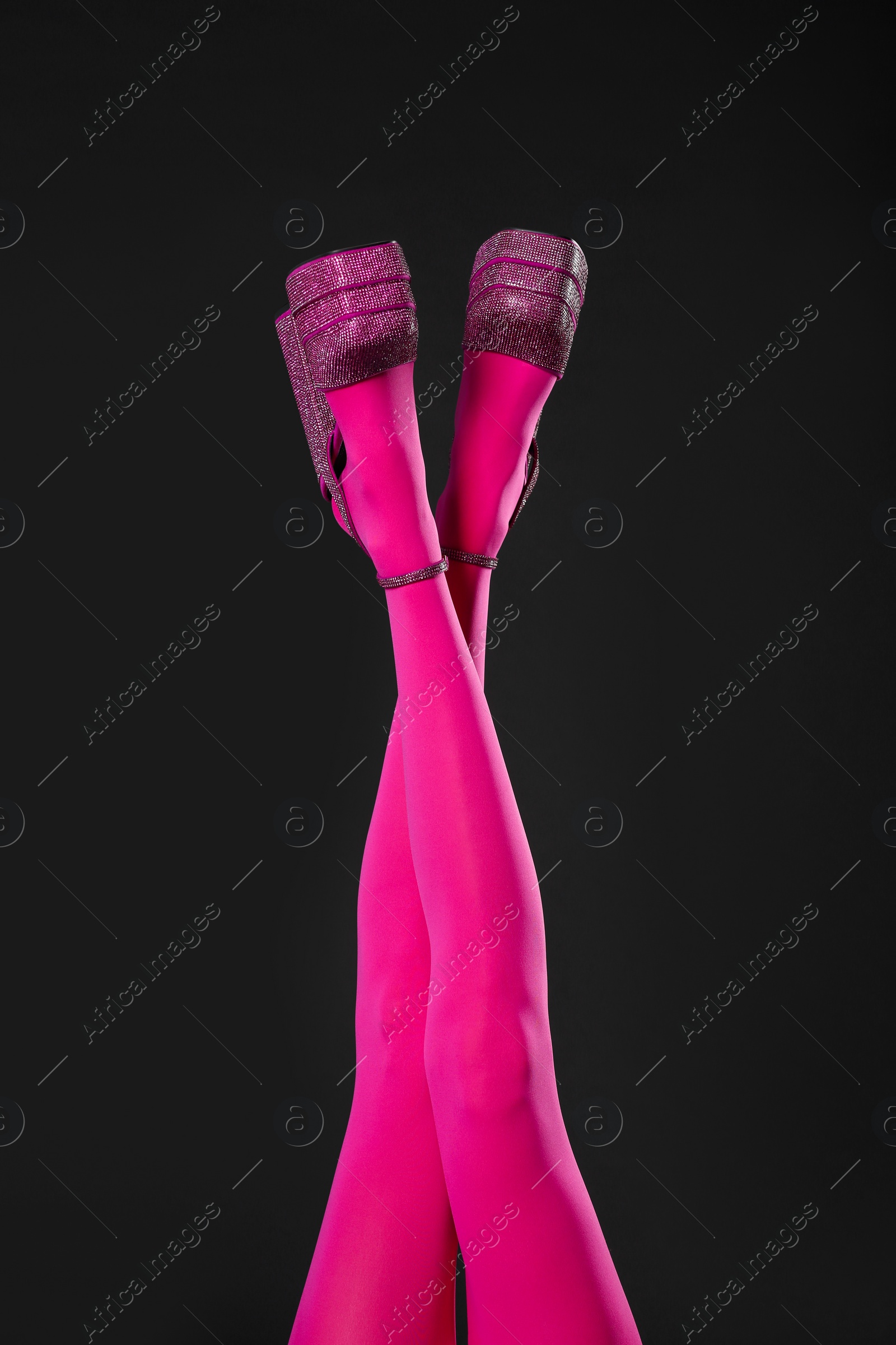 Photo of Woman wearing pink tights and high heeled shoes with platform and square toes on black background, closeup