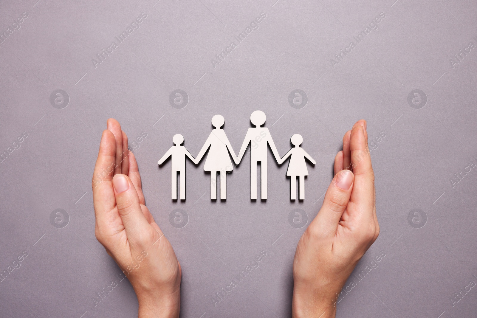 Photo of Woman protecting figures of family on lilac background, top view. Insurance concept