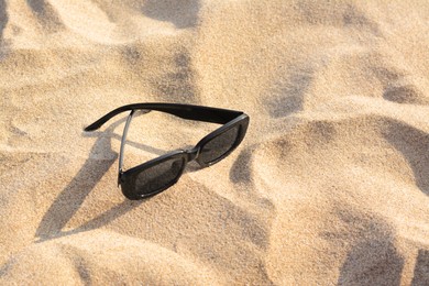 Photo of Stylish sunglasses on sandy beach, space for text
