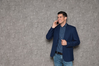 Portrait of businessman talking on phone against grey background. Space for text