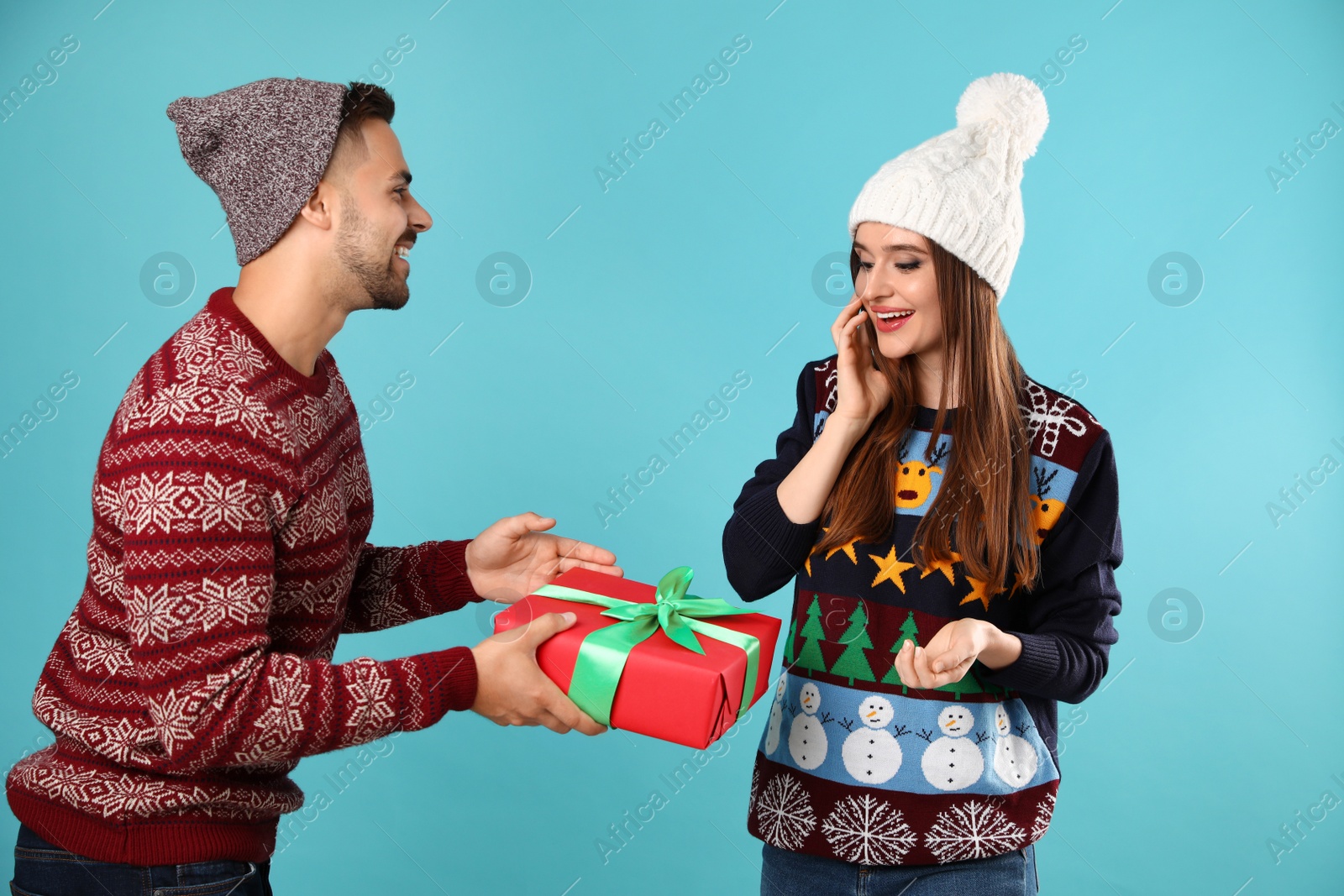 Photo of Couple wearing Christmas sweaters on blue background