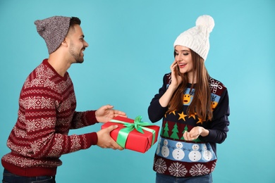 Couple wearing Christmas sweaters on blue background