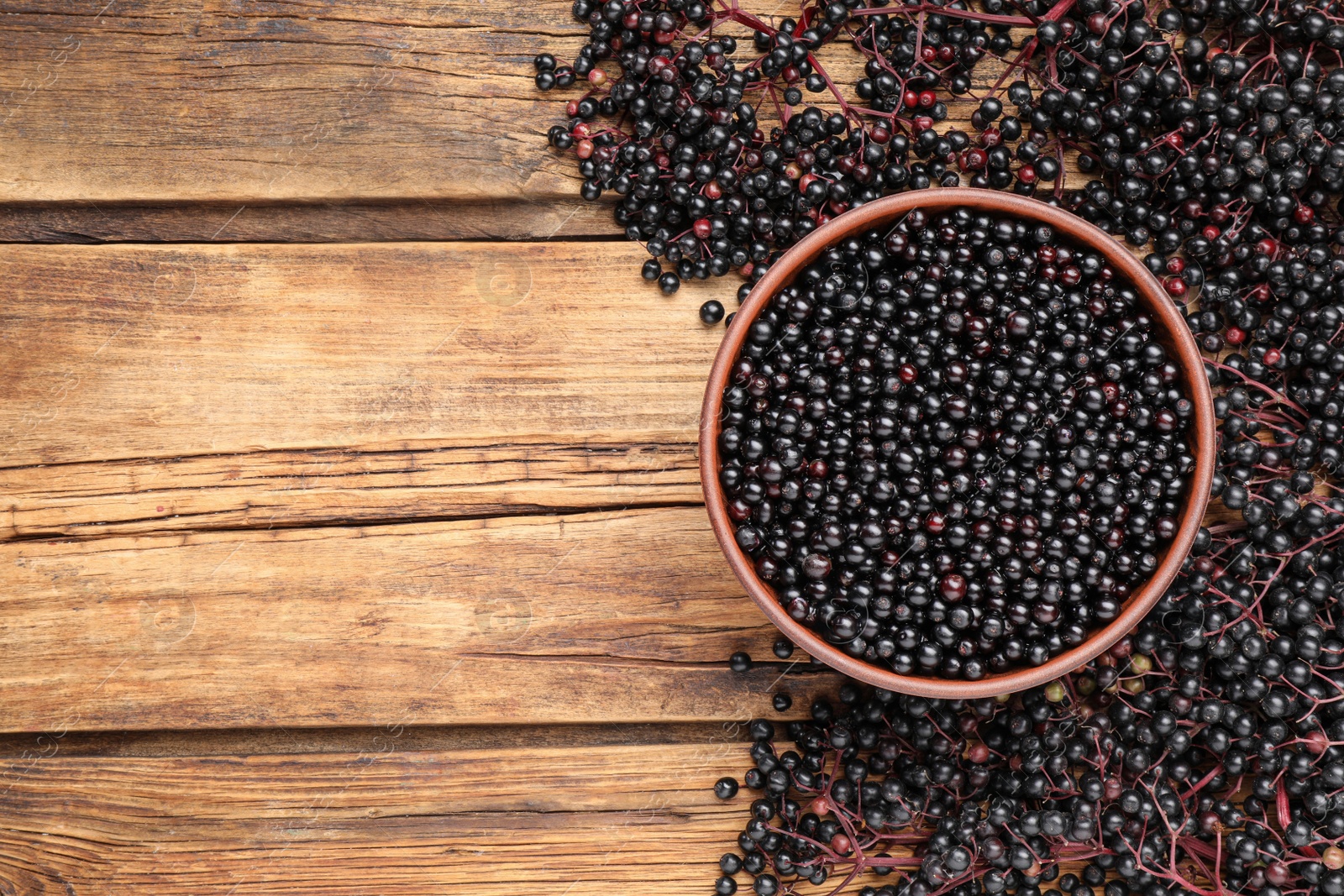 Photo of Elderberries (Sambucus) on wooden table, flat lay. Space for text