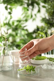 Photo of Scientist making cosmetic product at grey table, closeup