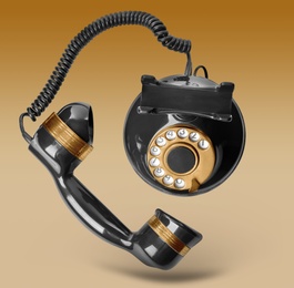 Image of Vintage black corded telephone flying in air on color background
