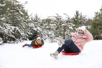 Happy couple sledding outdoors on winter day. Christmas vacation