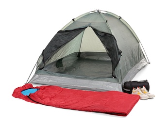 Photo of Comfortable grey camping tent with red sleeping bag and sneakers on white background