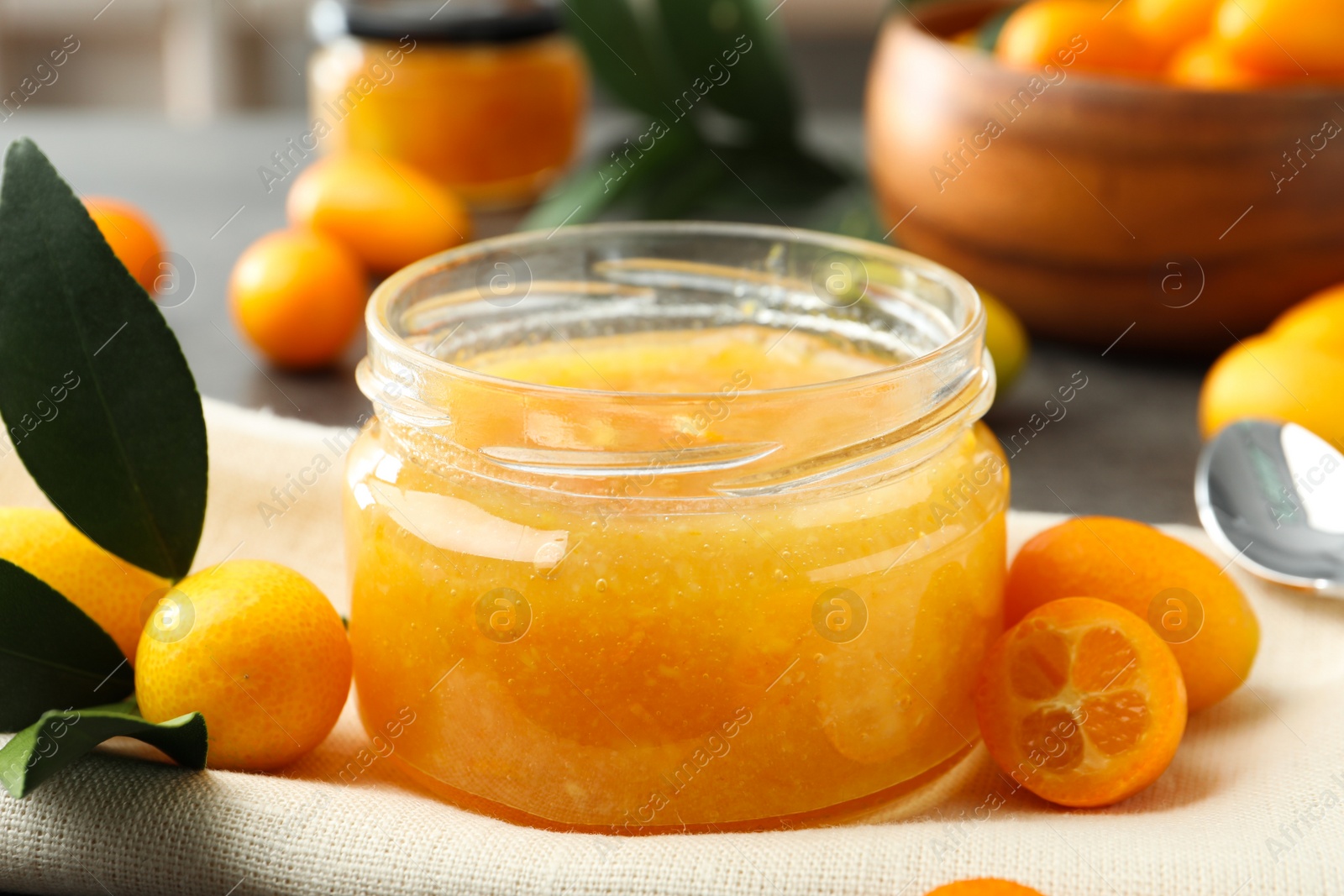 Photo of Delicious kumquat jam and fresh fruits on table, closeup