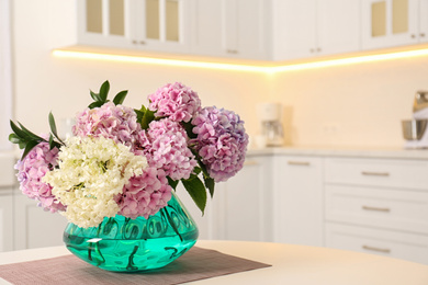 Photo of Bouquet of beautiful hydrangea flowers on table in kitchen, space for text. Interior design