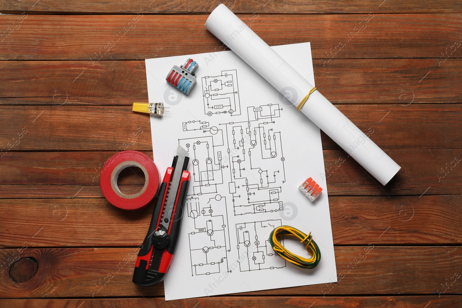 Photo of Wiring diagram, knife, different electrician's equipment and insulating tape on wooden table, flat lay