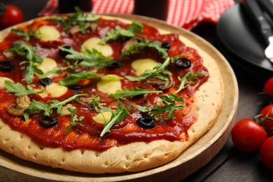 Pita pizza with cheese, olives, mushrooms and arugula on wooden table, closeup