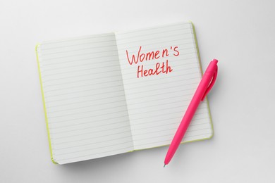 Photo of Notebook with words Women's Health and pen on white background, top view