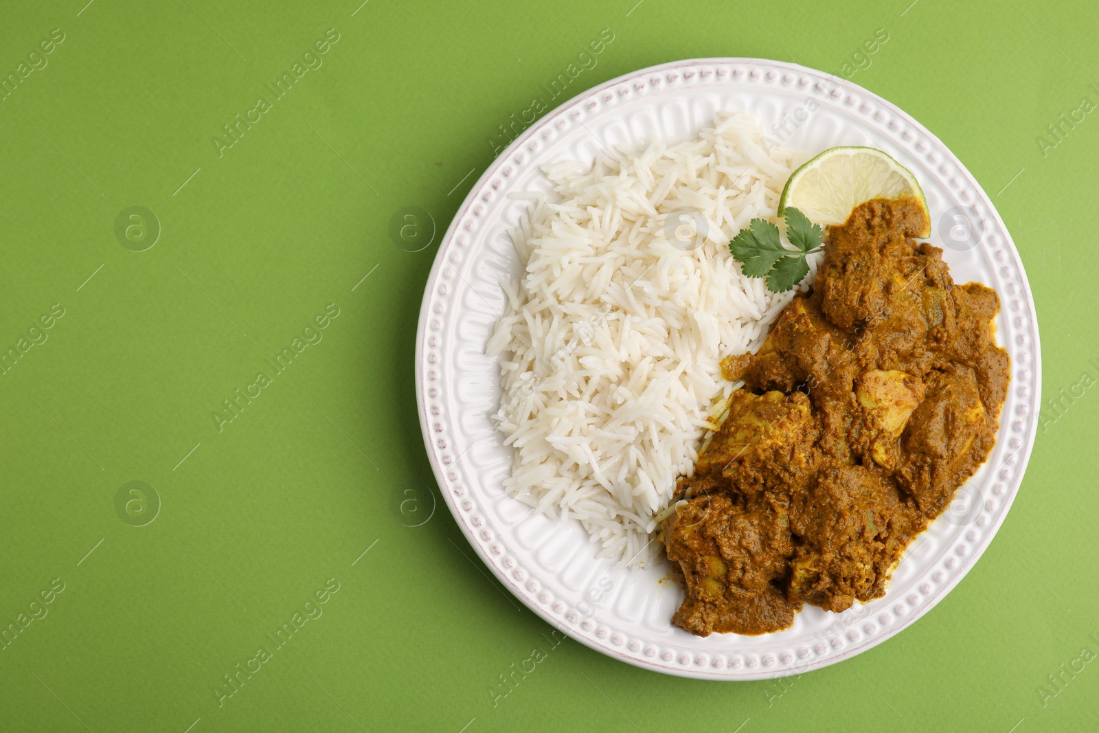 Photo of Delicious chicken curry with rice on green background, top view. Space for text