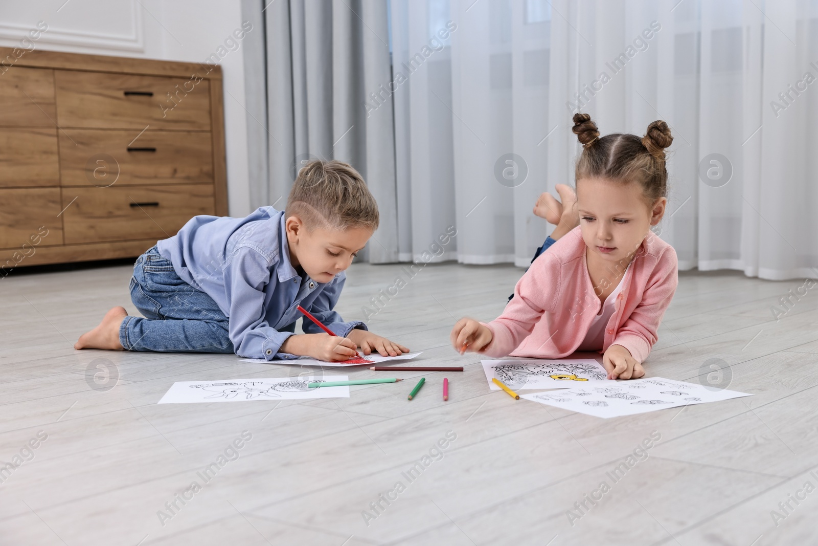 Photo of Cute little children coloring on warm floor at home. Heating system