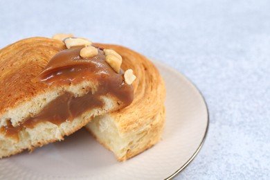 Photo of Tasty puff pastry. Supreme croissant with chocolate paste and nuts on grey table, closeup. Space for text