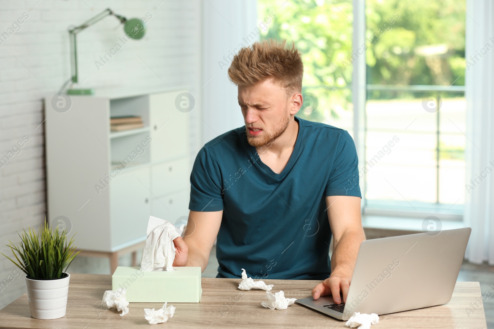 Photo of Young man suffering from allergy at home office