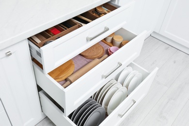 Photo of Open drawers with cutlery and utensils indoors. Order in kitchen