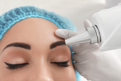 Photo of Woman undergoing laser tattoo removal procedure in salon, closeup