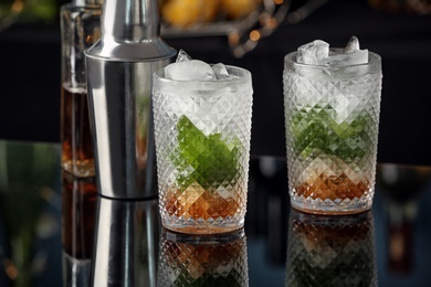 Photo of Delicious mint julep cocktail in glasses on bar counter