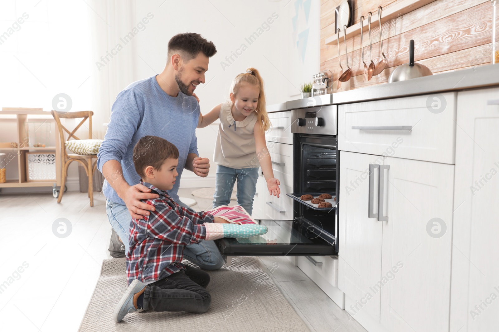 Photo of Father with his kids baking cookies in oven at home
