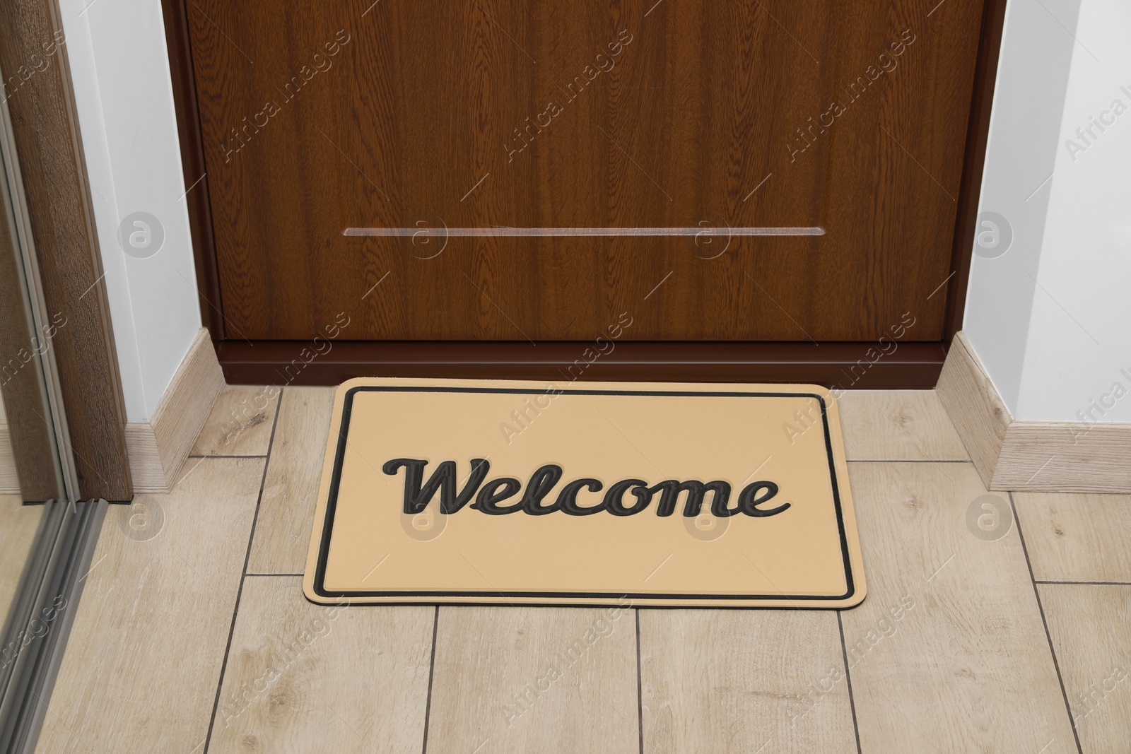 Photo of Beautiful beige doormat with word Welcome on floor near entrance