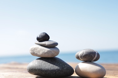 Photo of Stacks of stones on wooden pier near sea. Zen concept