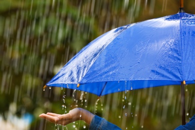 Photo of Woman with bright umbrella under rain on street, closeup