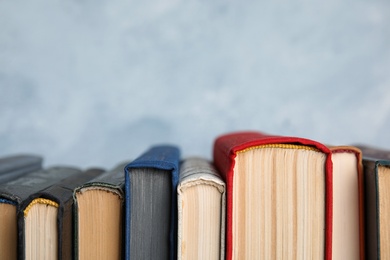 Photo of Stack of hardcover books on light blue background, closeup. Space for text