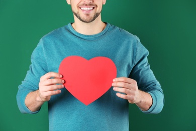 Man with decorative heart on color background, closeup