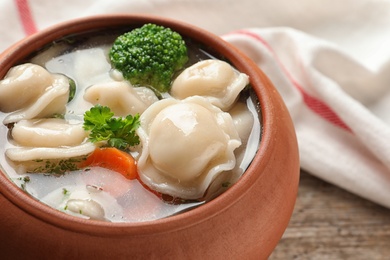 Photo of Pot of tasty dumplings with broth and vegetables on table, closeup. Space for text