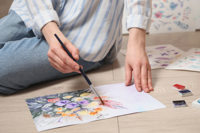 Photo of Woman painting flowers with watercolor on floor, closeup