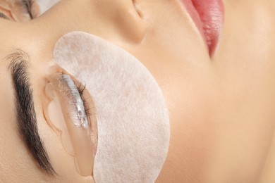Young woman undergoing eyelash lamination, closeup. Professional service
